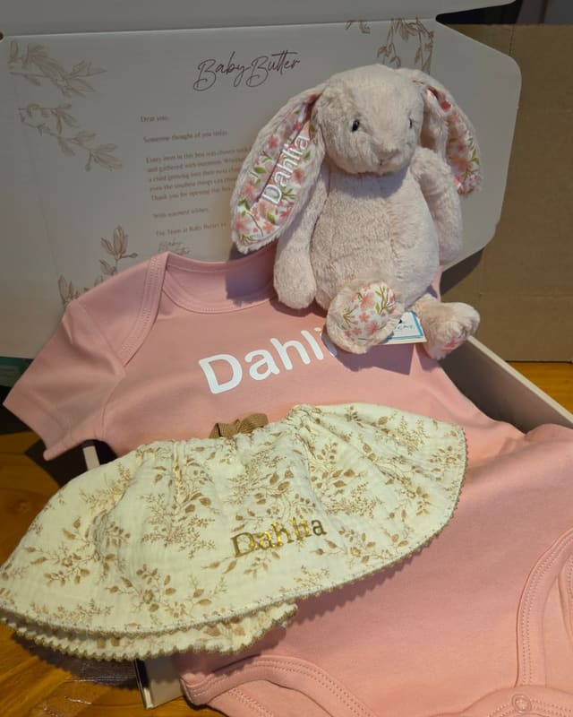 A gift box with a personalised Jellycat bunny, a pink romper and a floral bucket hat, named for Dani