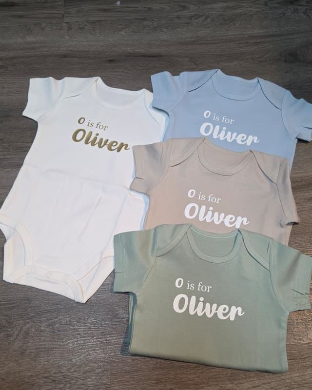 Four rompers in different colours printed O is for Oliver